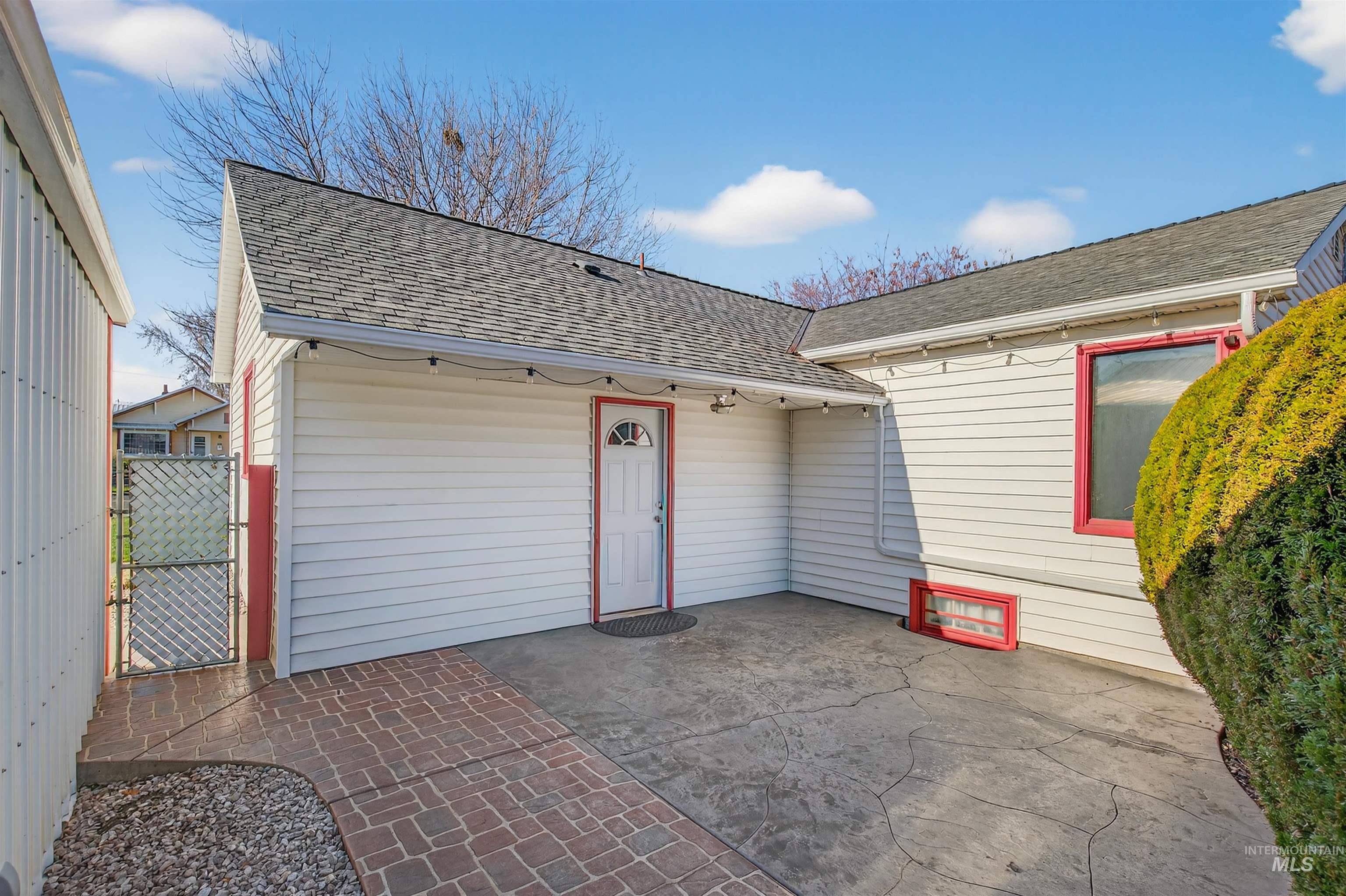 Rear view of house featuring a shingled roof, a patio area, and a gate
