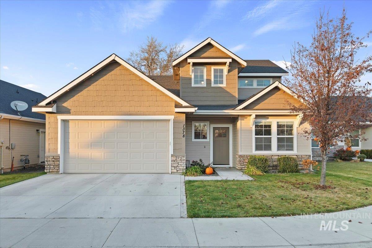 Craftsman-style house featuring stone siding, driveway, a front yard, and an attached garage