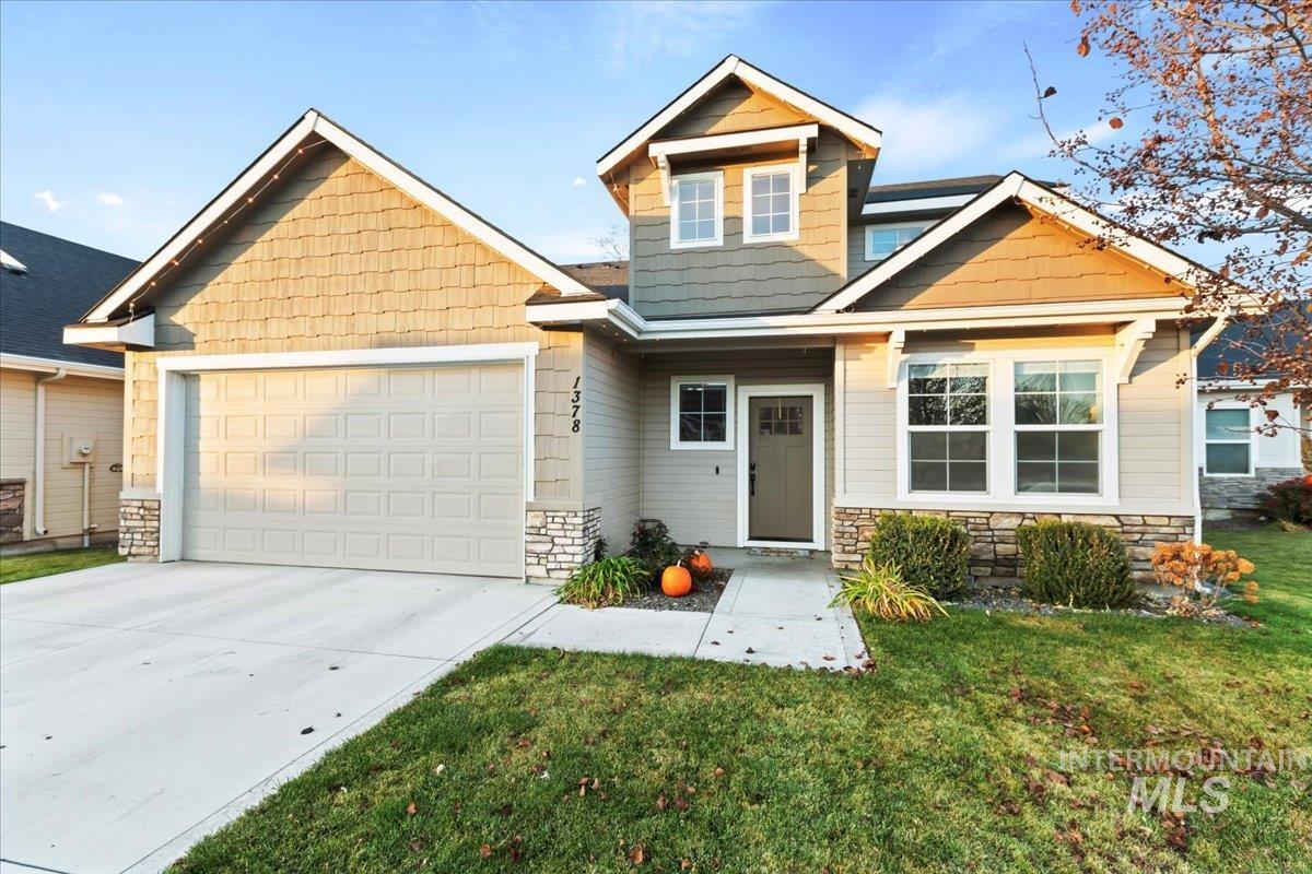 Craftsman house featuring stone siding, concrete driveway, a front lawn, and an attached garage