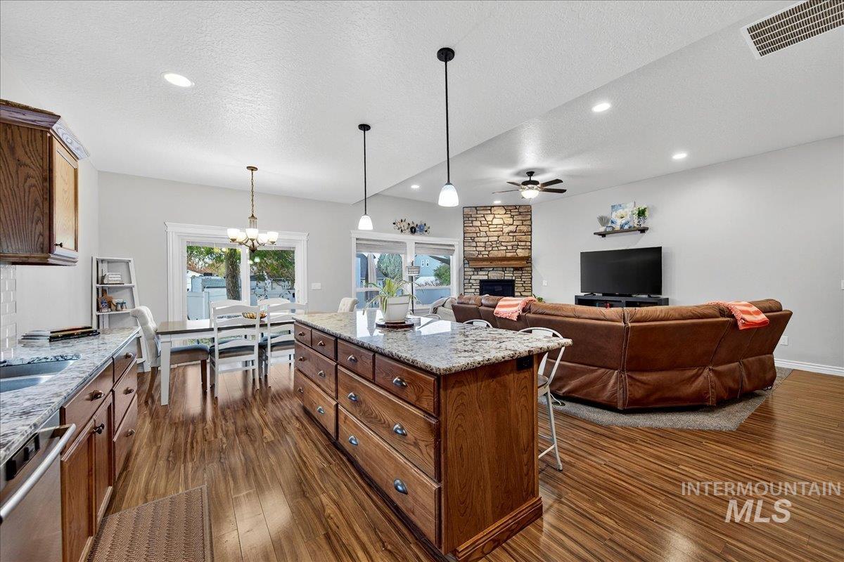 Kitchen featuring a textured ceiling, light stone countertops, pendant lighting, a breakfast bar, and a fireplace