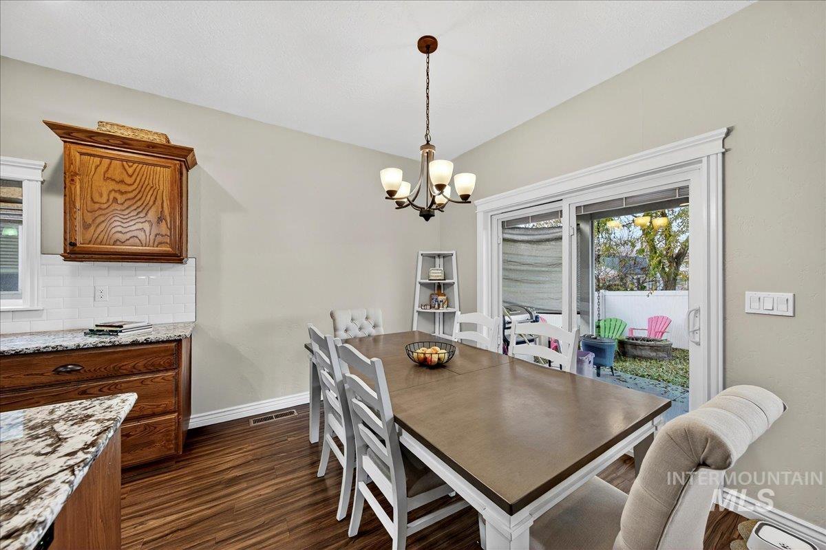 Dining room with dark wood-type flooring and a chandelier