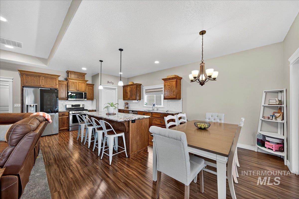 Dining room with dark wood-style flooring, a chandelier, a textured ceiling, and recessed lighting
