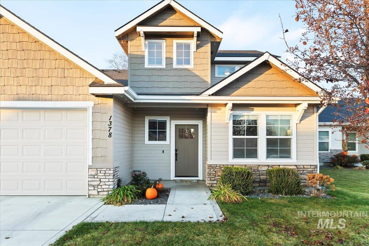 Craftsman-style home featuring stone siding, a front lawn, and an attached garage