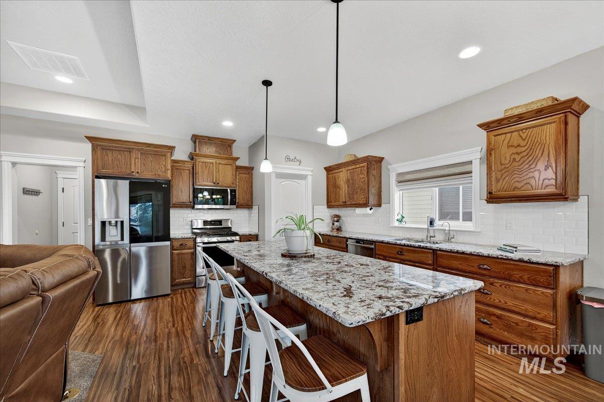 Kitchen featuring appliances with stainless steel finishes, backsplash, dark wood-style floors, and recessed lighting