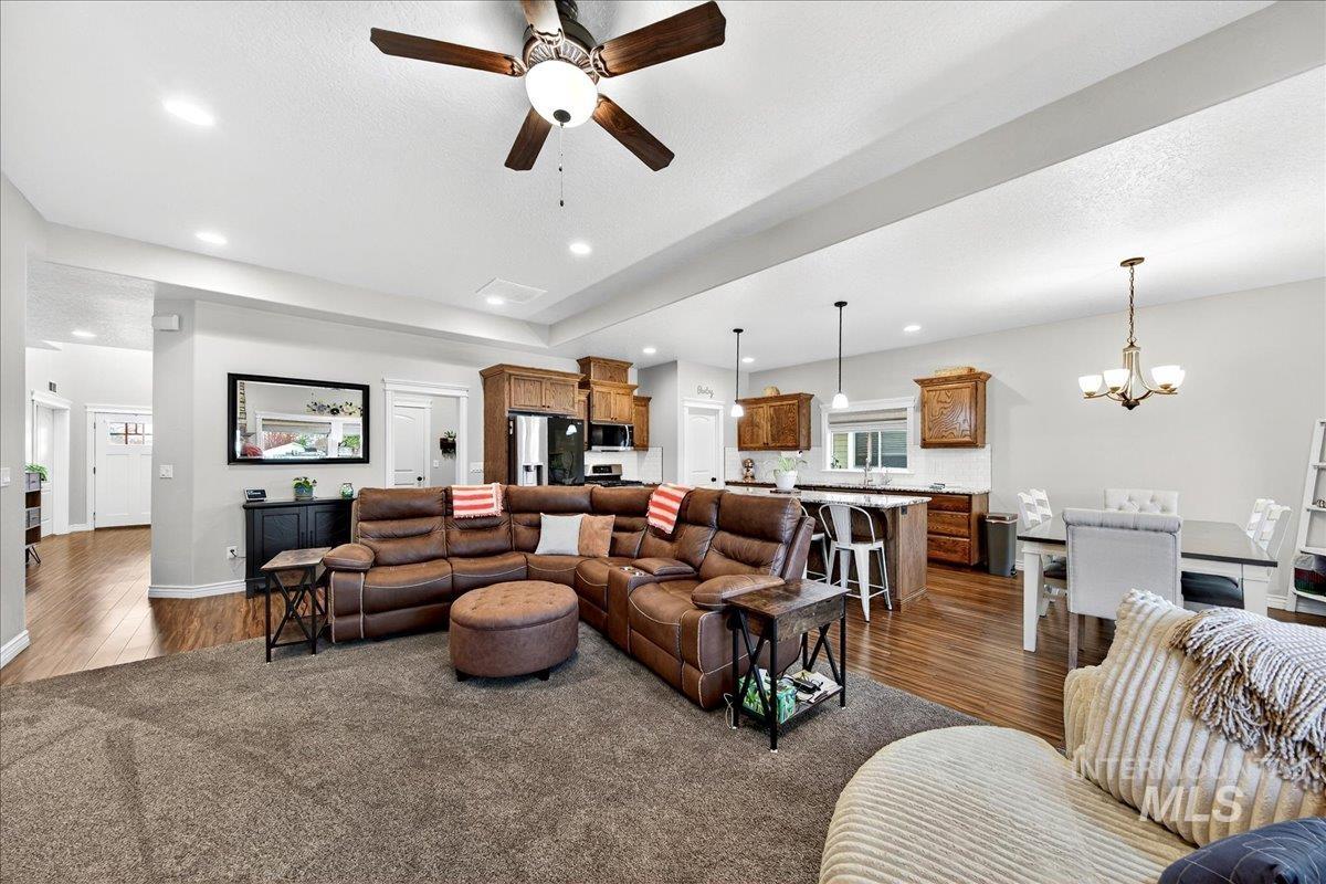 Living area featuring dark wood finished floors, a ceiling fan, recessed lighting, and a chandelier