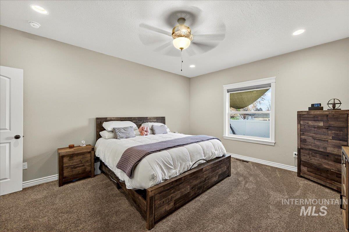Carpeted bedroom featuring recessed lighting, a ceiling fan, and a textured ceiling