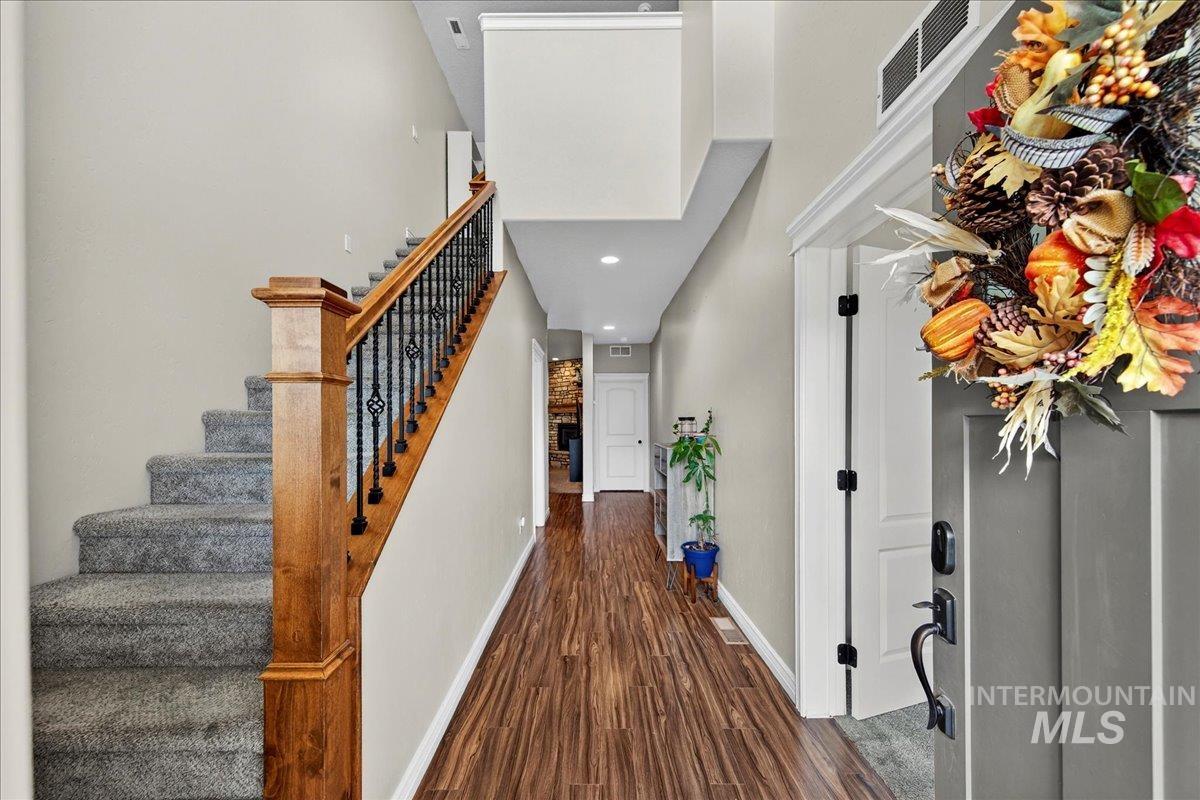 Entryway featuring dark wood-type flooring, a fireplace, stairway, and recessed lighting