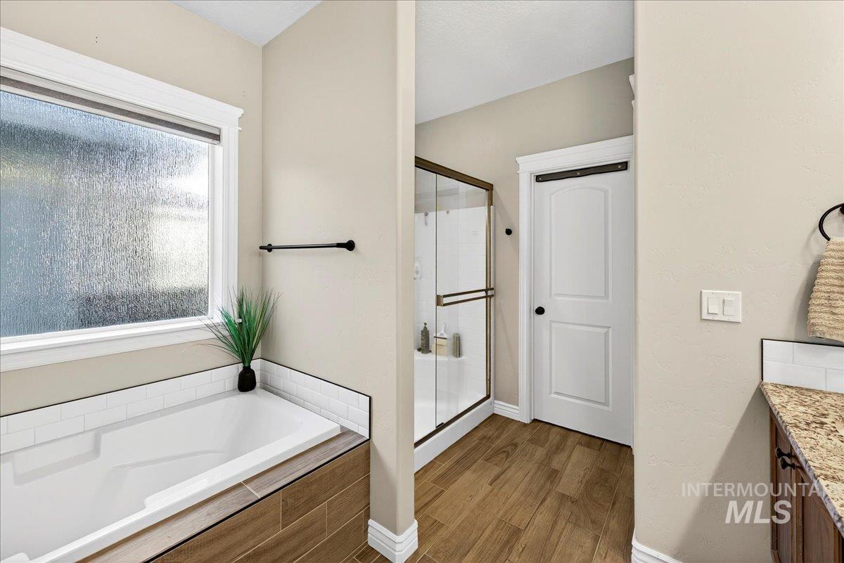 Bathroom featuring a stall shower, light wood-style floors, vanity, and a garden tub