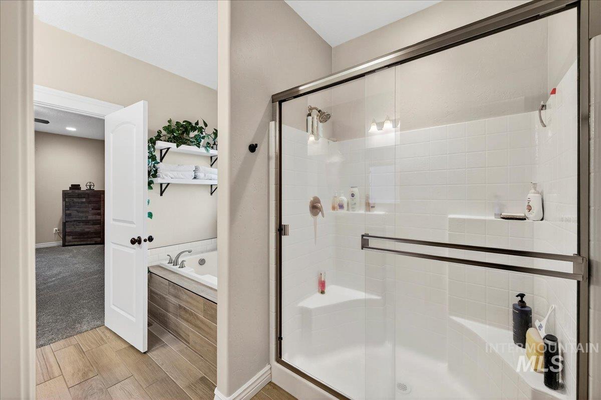 Bathroom featuring a garden tub, a shower stall, and wood tiled floors