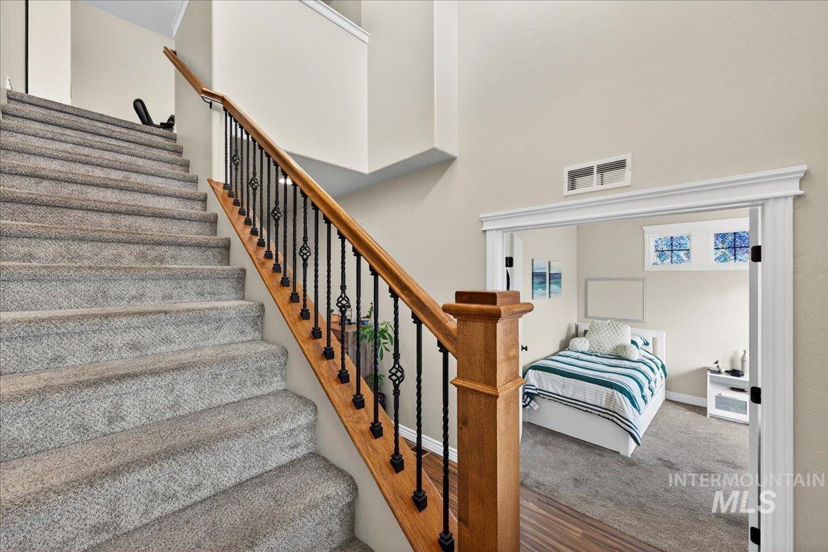 Stairs with carpet flooring, a high ceiling, and wood finished floors