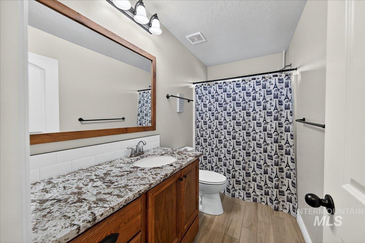 Bathroom featuring light wood-style floors, a textured ceiling, vanity, and a shower with curtain