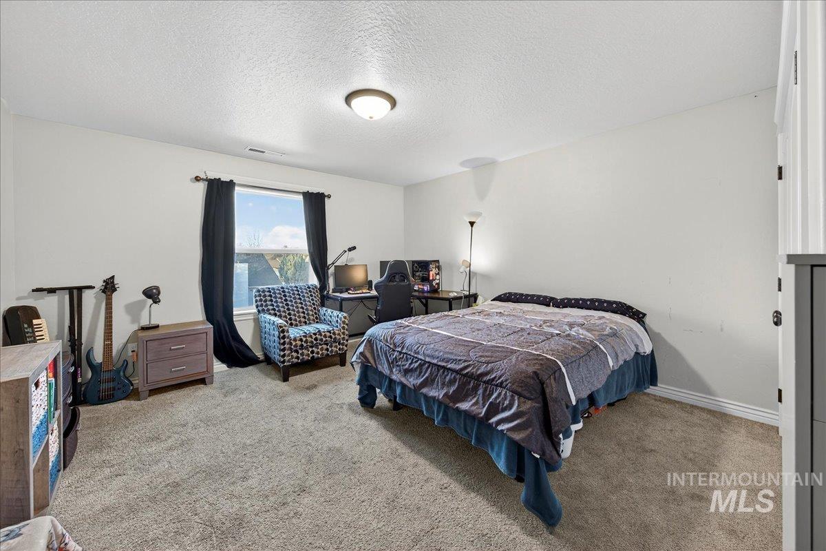 Carpeted bedroom with a textured ceiling and baseboards