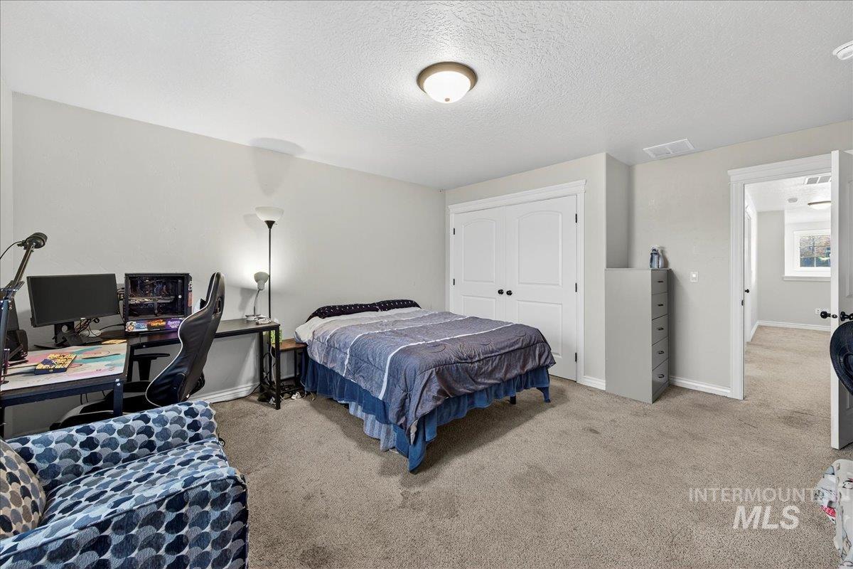 Bedroom with a desk, carpet floors, a textured ceiling, and a closet