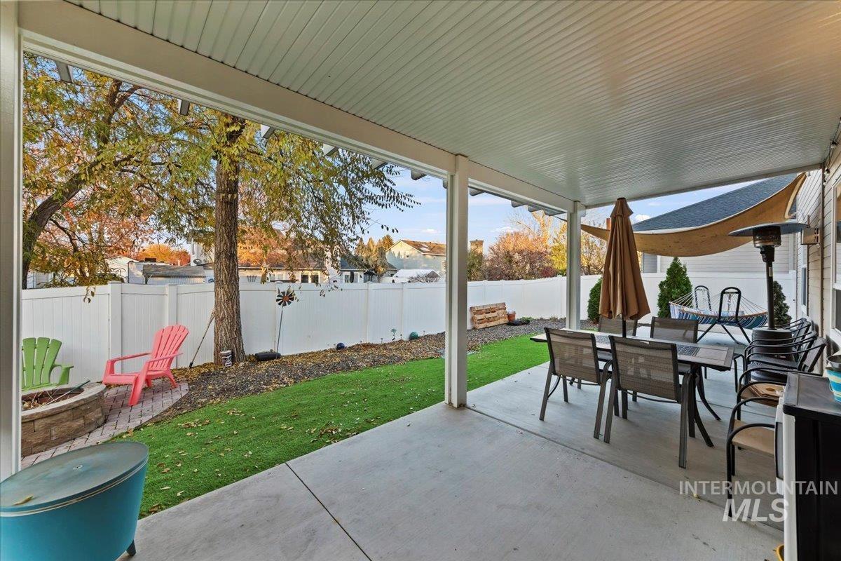 Fenced backyard with a patio area, outdoor dining space, and a fire pit