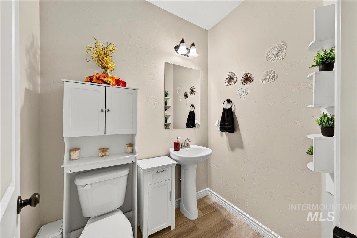 Half bath with light wood-style flooring and a textured wall