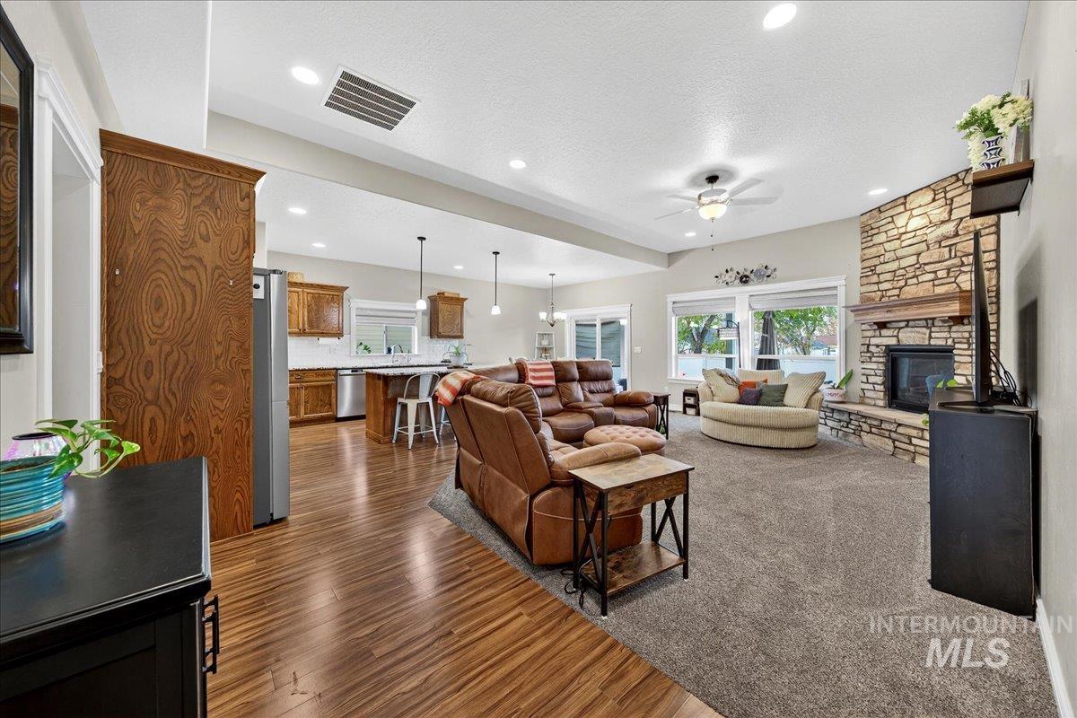 Living area with a fireplace, dark wood-style floors, a textured ceiling, a ceiling fan, and recessed lighting