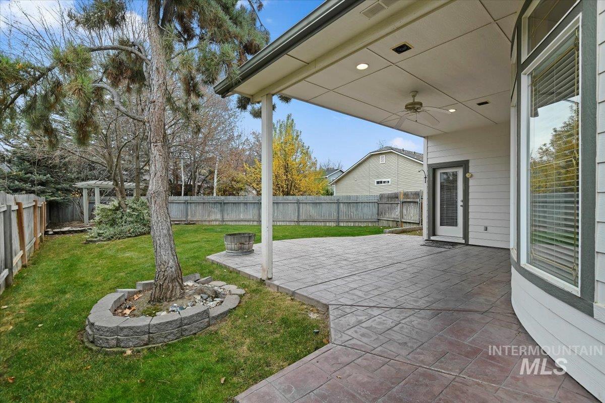 Fenced backyard with ceiling fan and a patio area