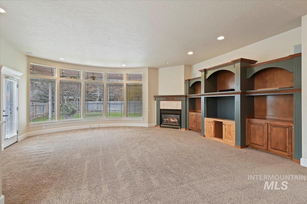 Unfurnished living room with recessed lighting, light carpet, a fireplace, and a textured ceiling