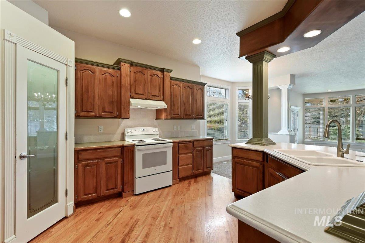 Kitchen with electric range, light countertops, a textured ceiling, light wood-style floors, and recessed lighting