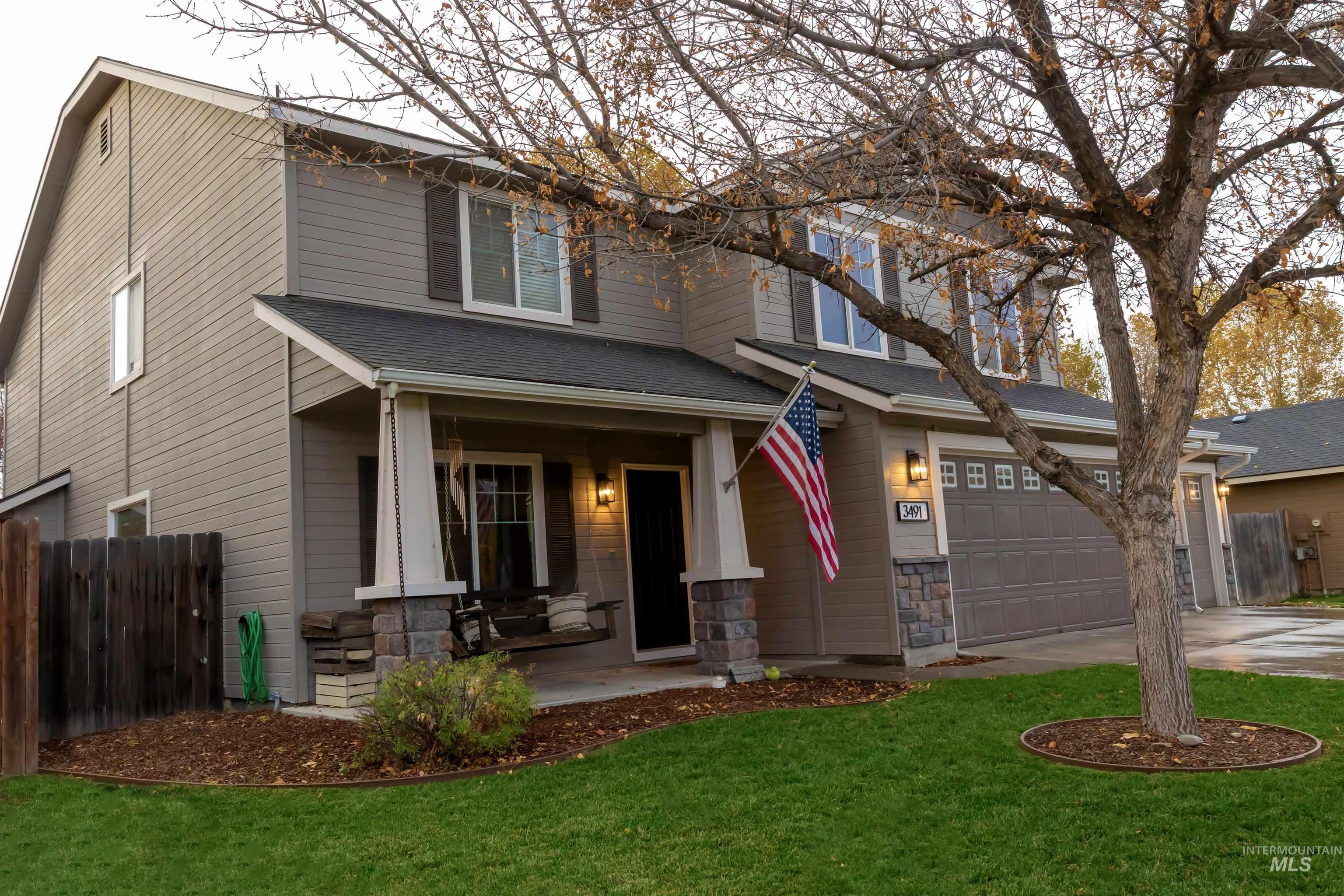 View of front facade featuring covered porch, stone siding, a garage, and concrete driveway