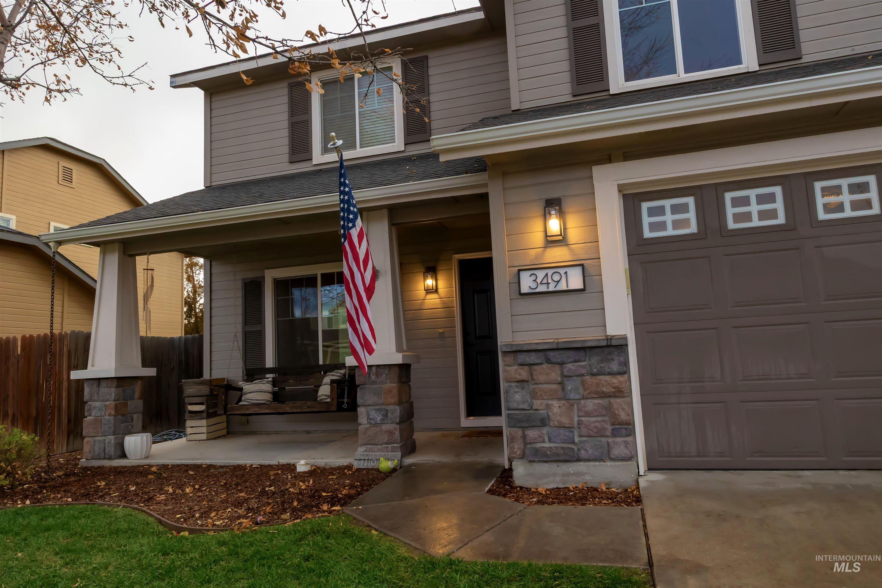 Property entrance with a porch, a garage, stone siding, and a shingled roof