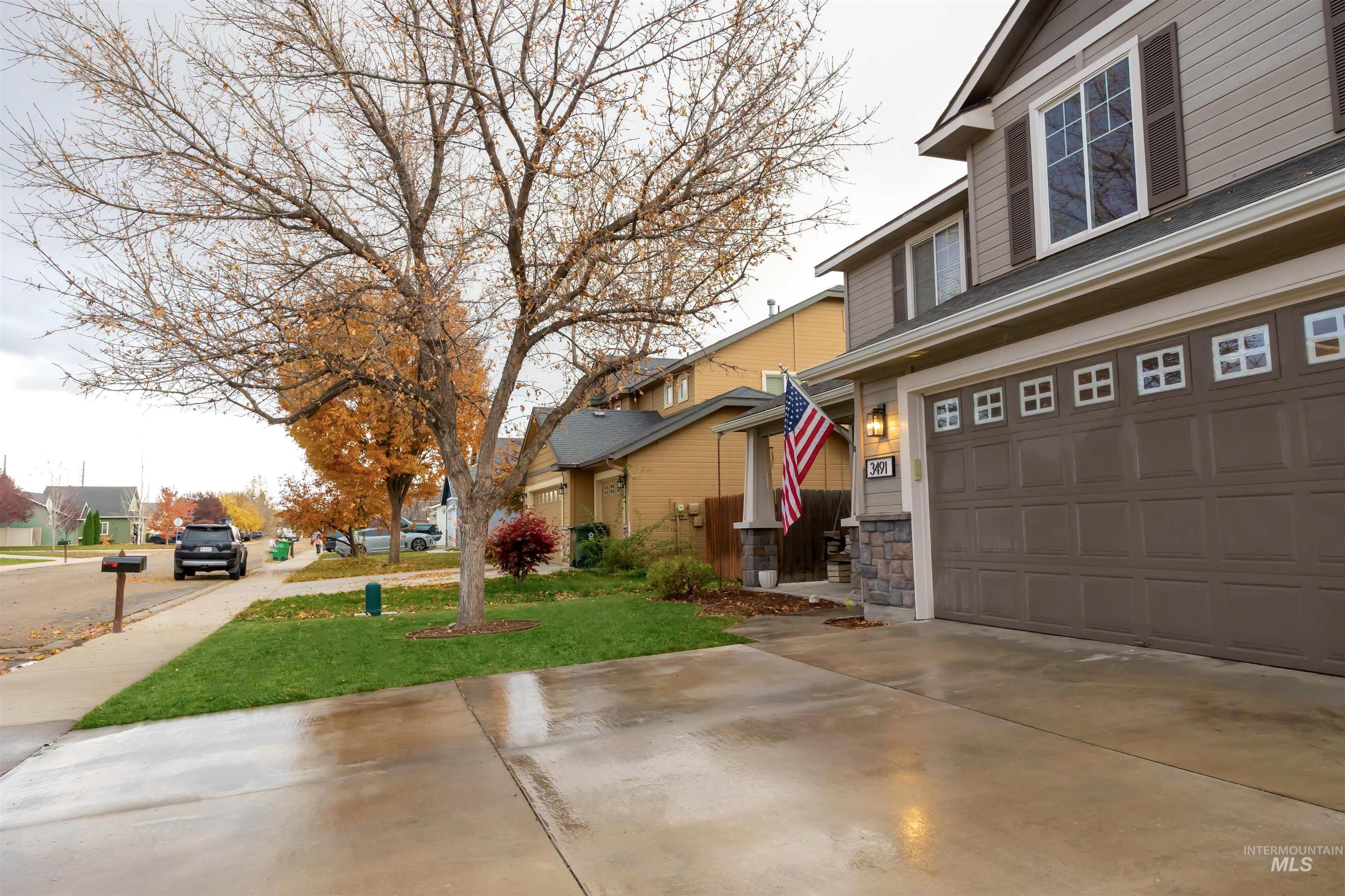 View of property exterior with a yard, a residential view, stone siding, concrete driveway, and a garage