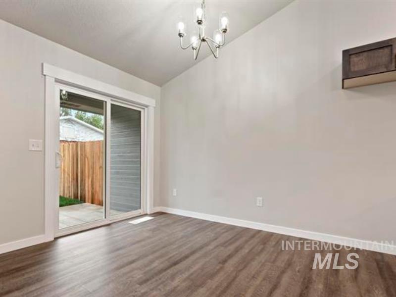 Vaulted ceiling, dark wood-style floors, and a chandelier