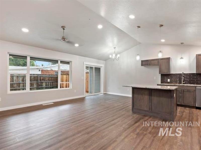 Great room with lofted ceiling, open floor plan, ample natural light, and dark wood-style flooring
