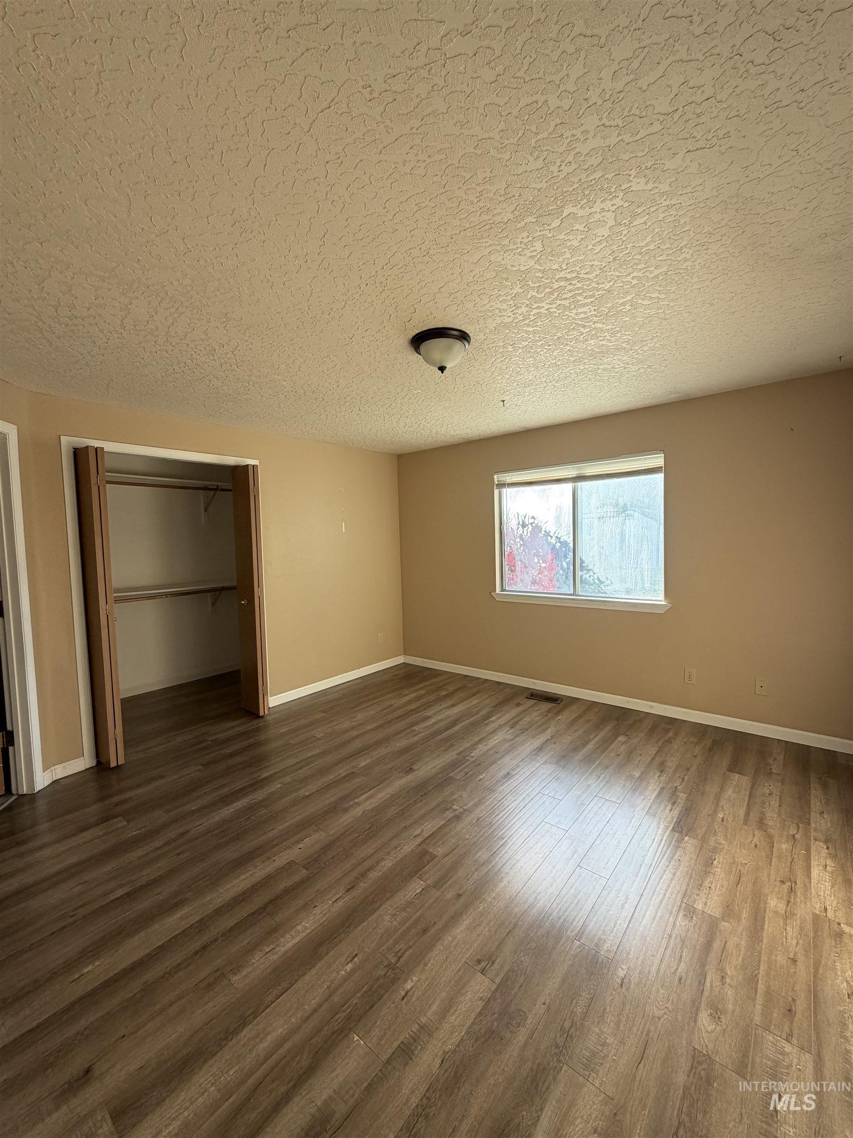 Unfurnished bedroom with wood finished floors and a textured ceiling