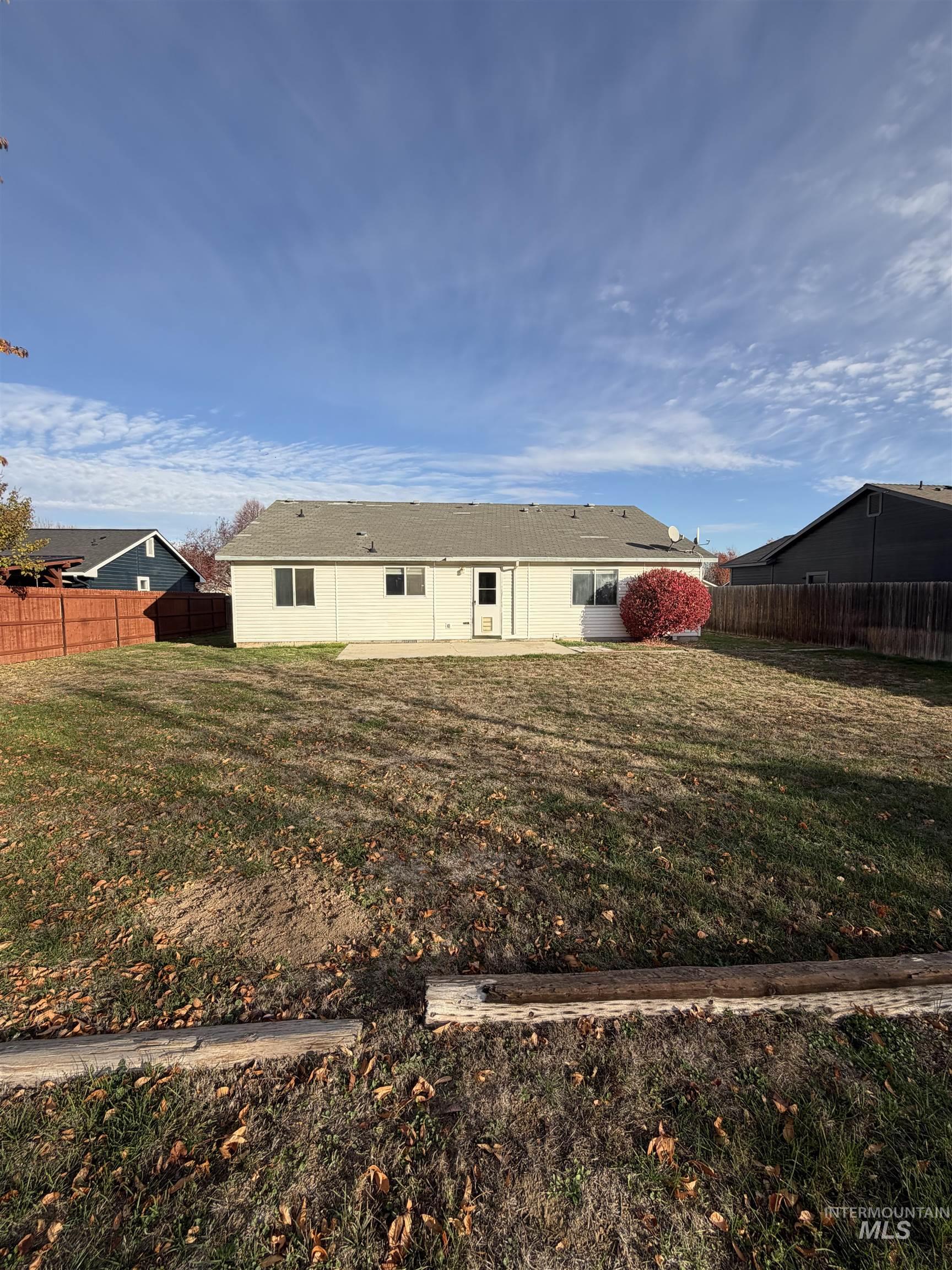 Back of house with a fenced backyard and a patio
