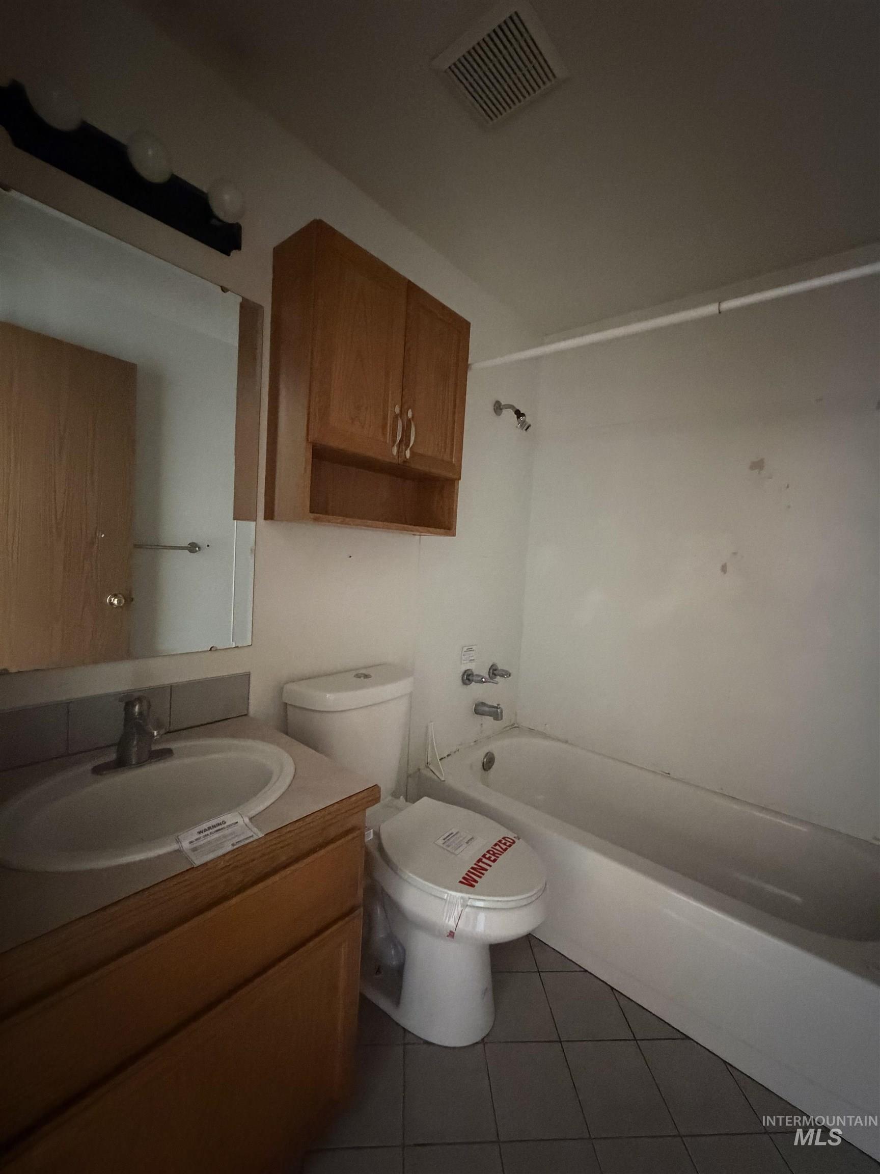 Bathroom with vanity, dark tile patterned floors, and shower / tub combination