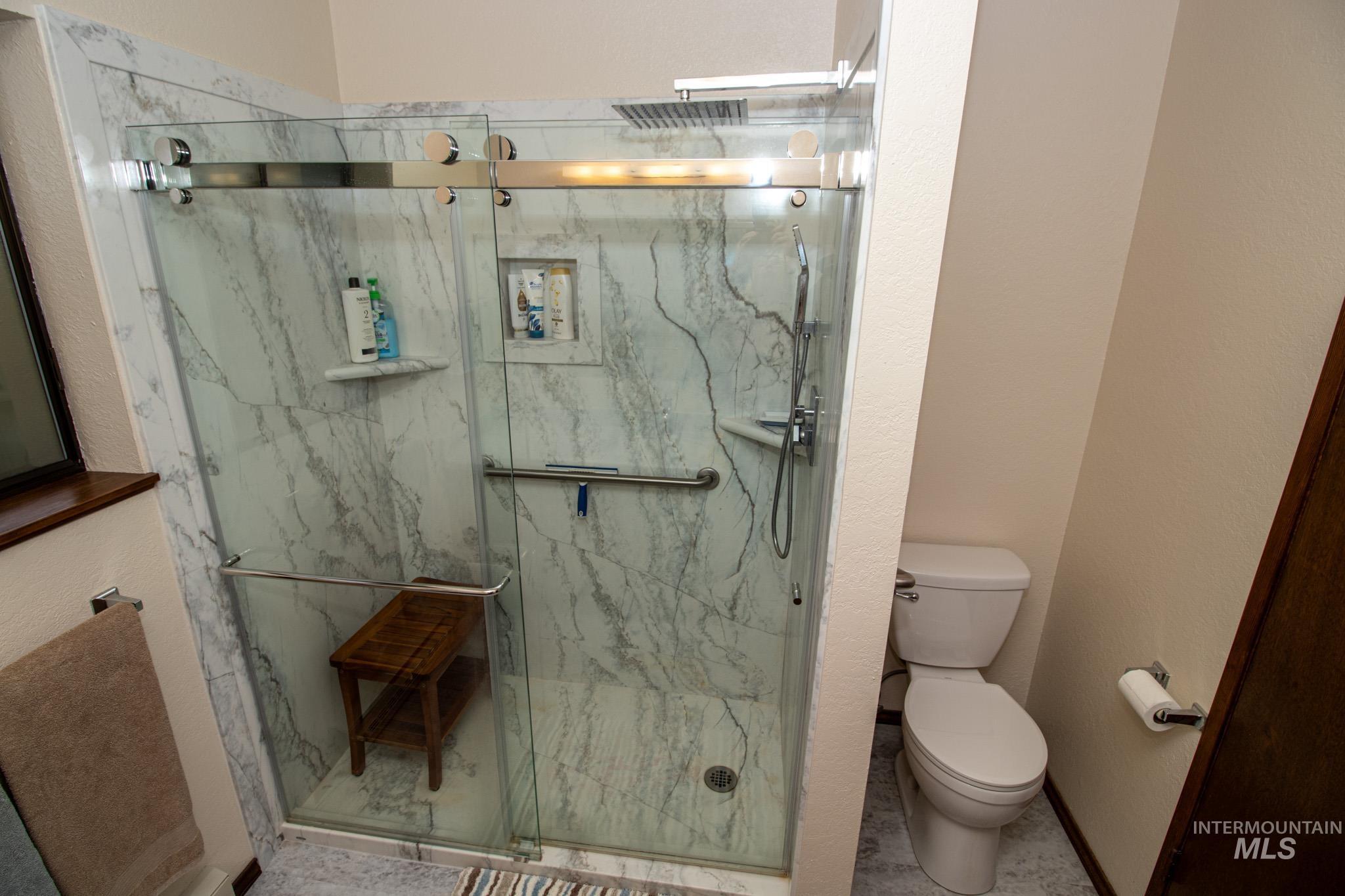 Full bathroom with a marble finish shower and a textured wall