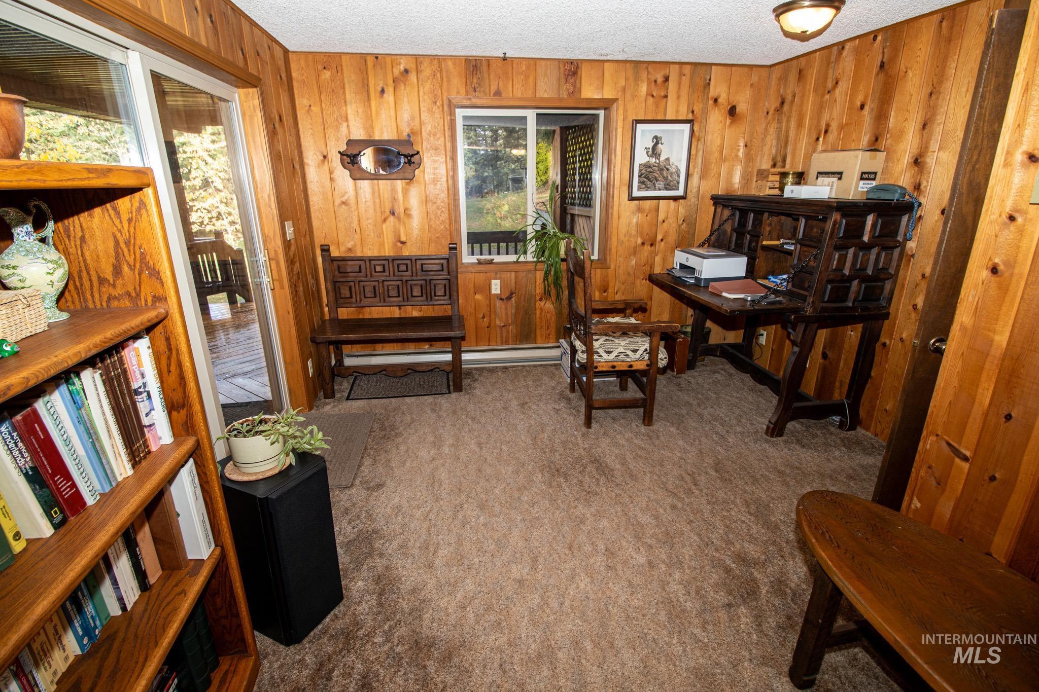 Carpeted office with a textured ceiling and wooden walls