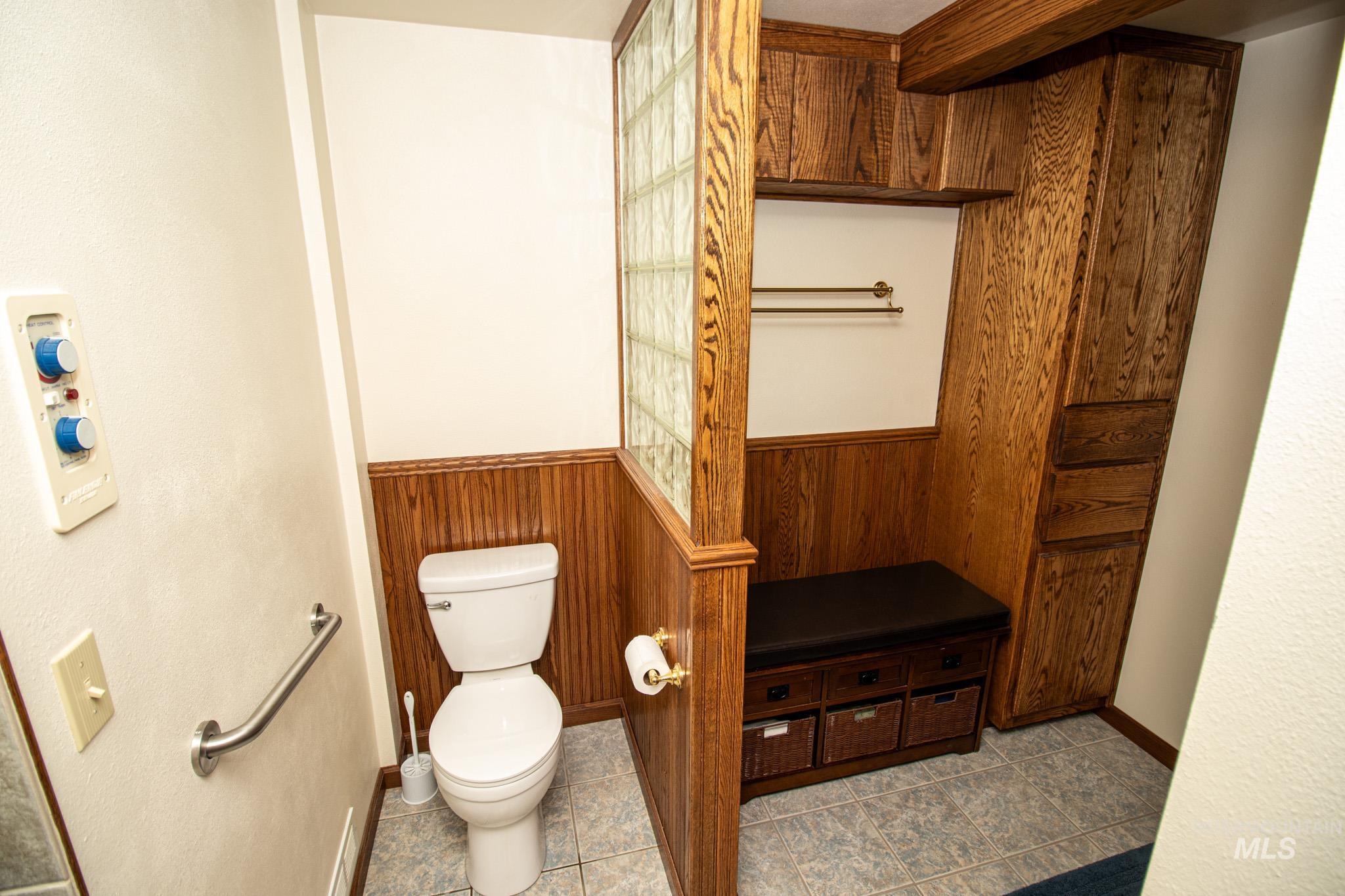 Half bathroom with wooden walls and tile patterned flooring