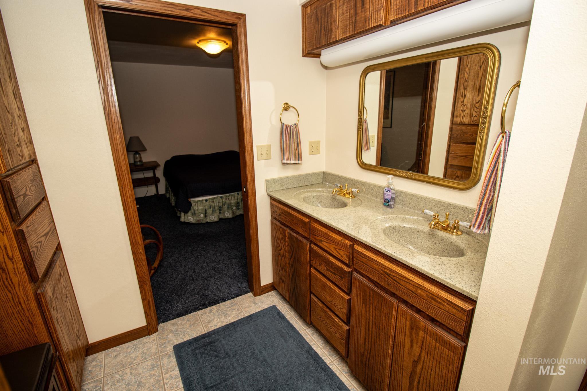 Full bath with double vanity, connected bathroom, and light tile patterned flooring