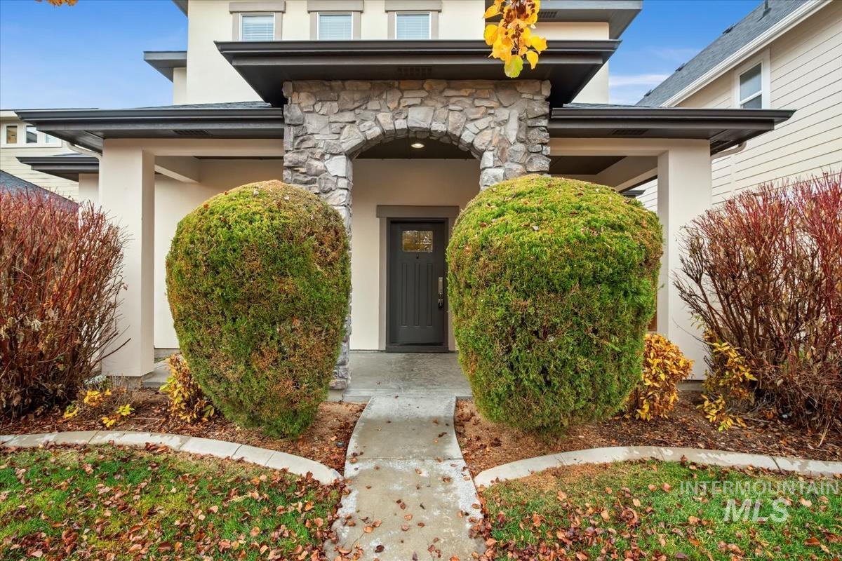 Doorway to property with stone siding, stucco siding, and a porch