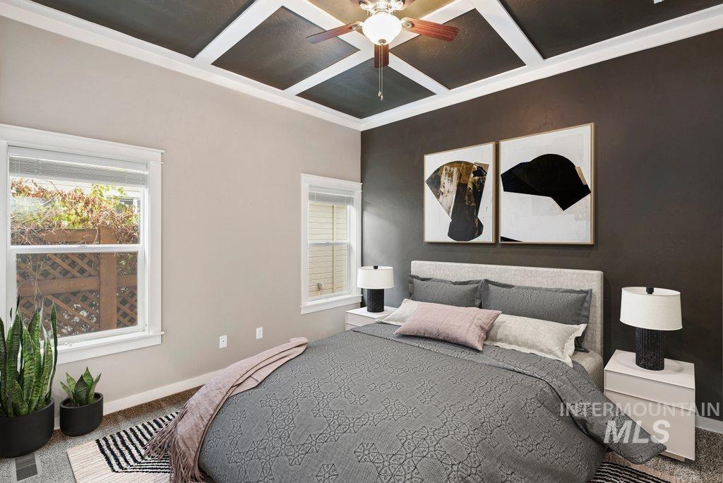 Carpeted bedroom with coffered ceiling, ceiling fan, and beamed ceiling