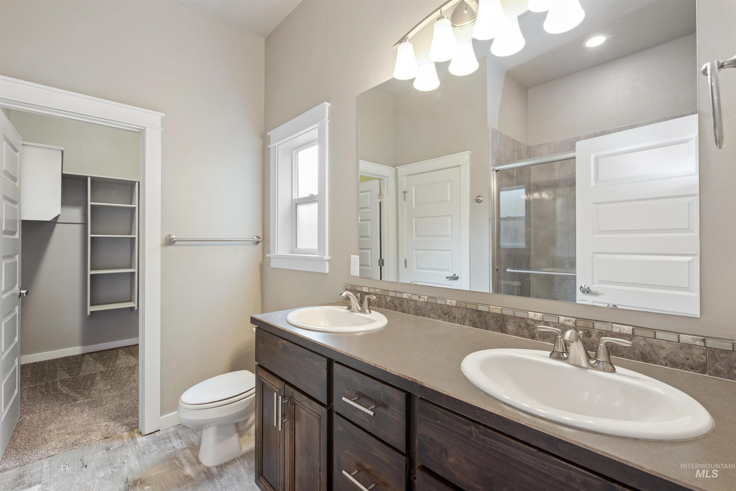 Bathroom with double vanity, a walk in closet, and a shower stall