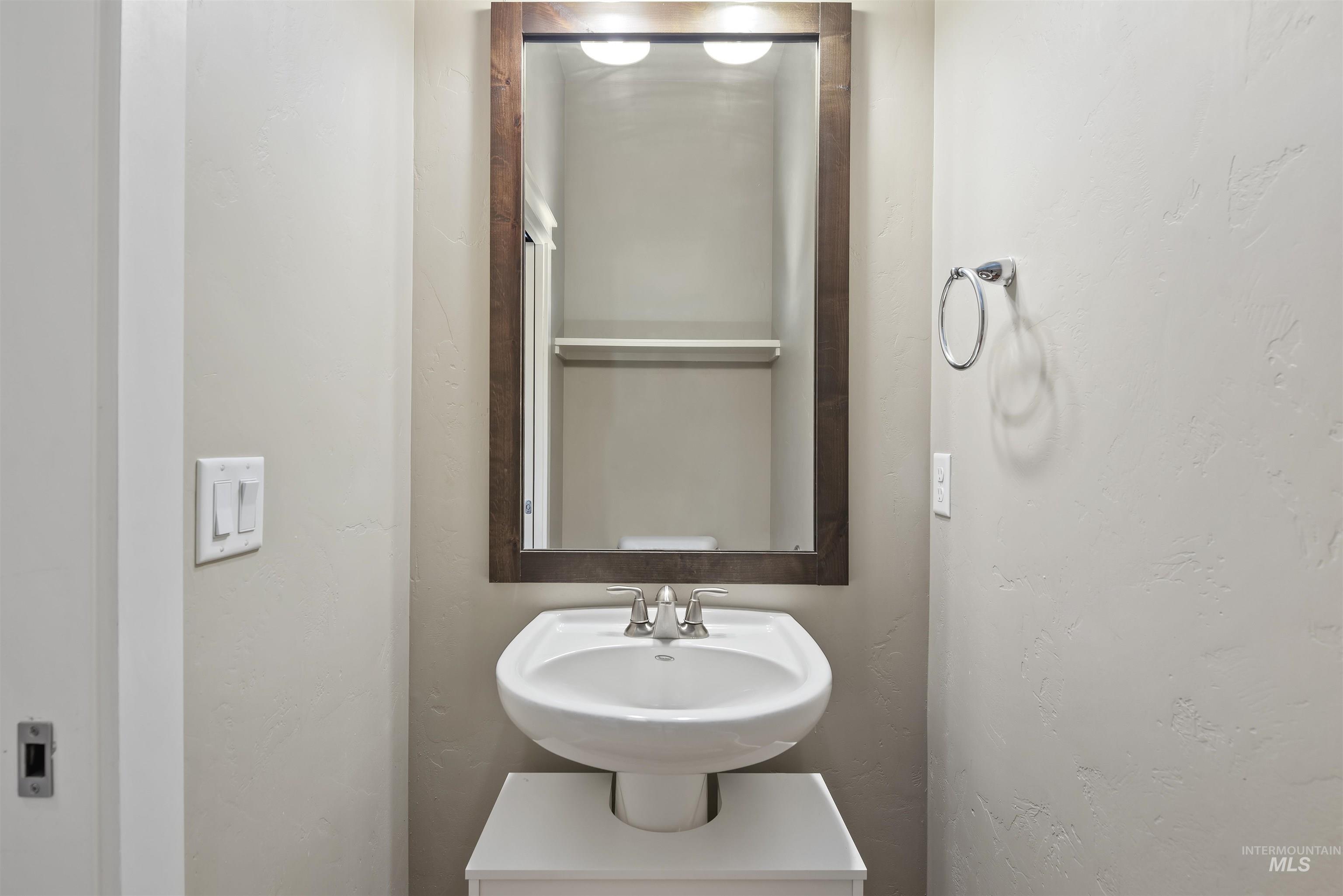Half bathroom featuring a textured wall and a sink