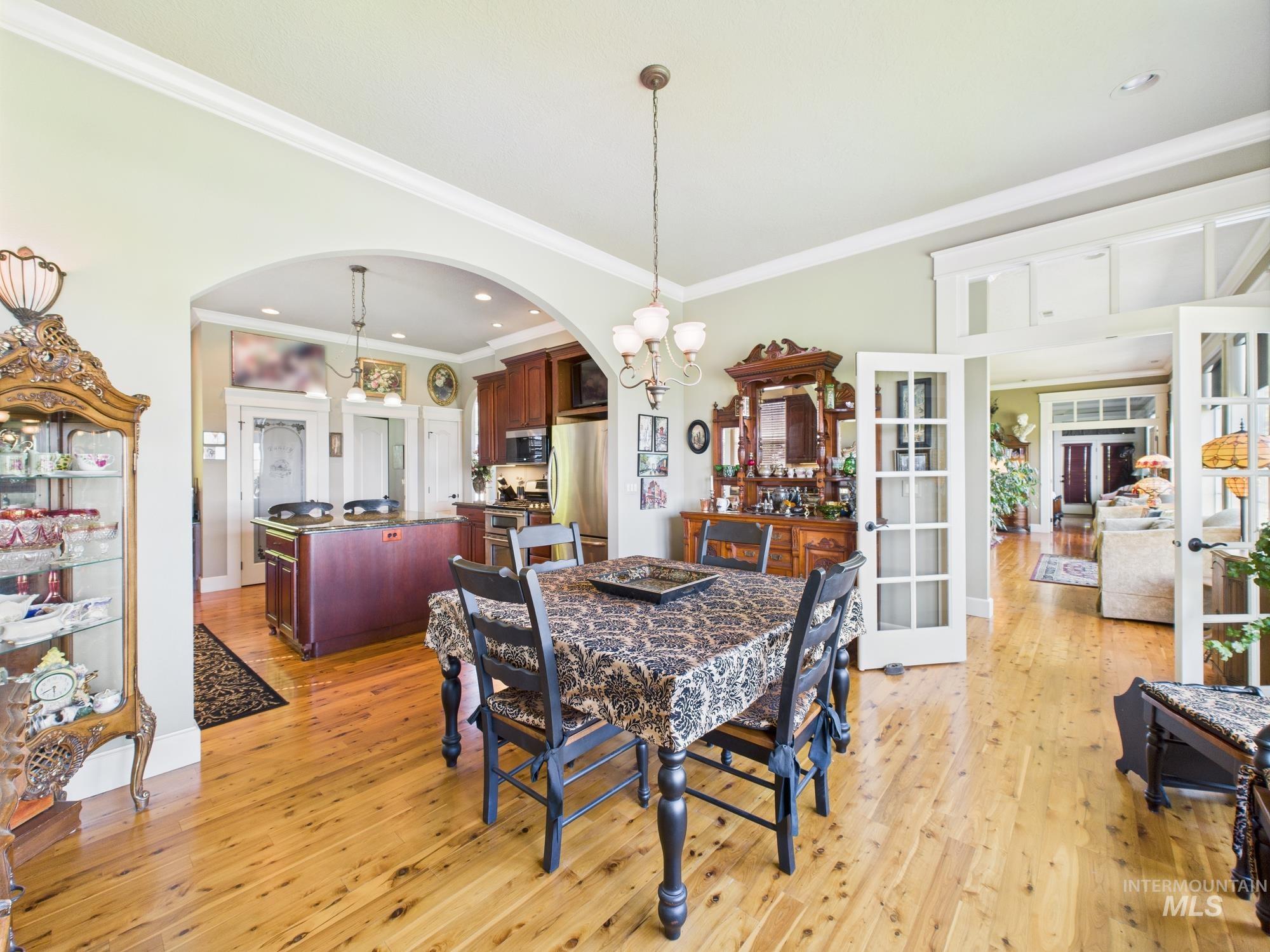 Dining area featuring light wood-style floors, crown molding, a chandelier, arched walkways, and recessed lighting