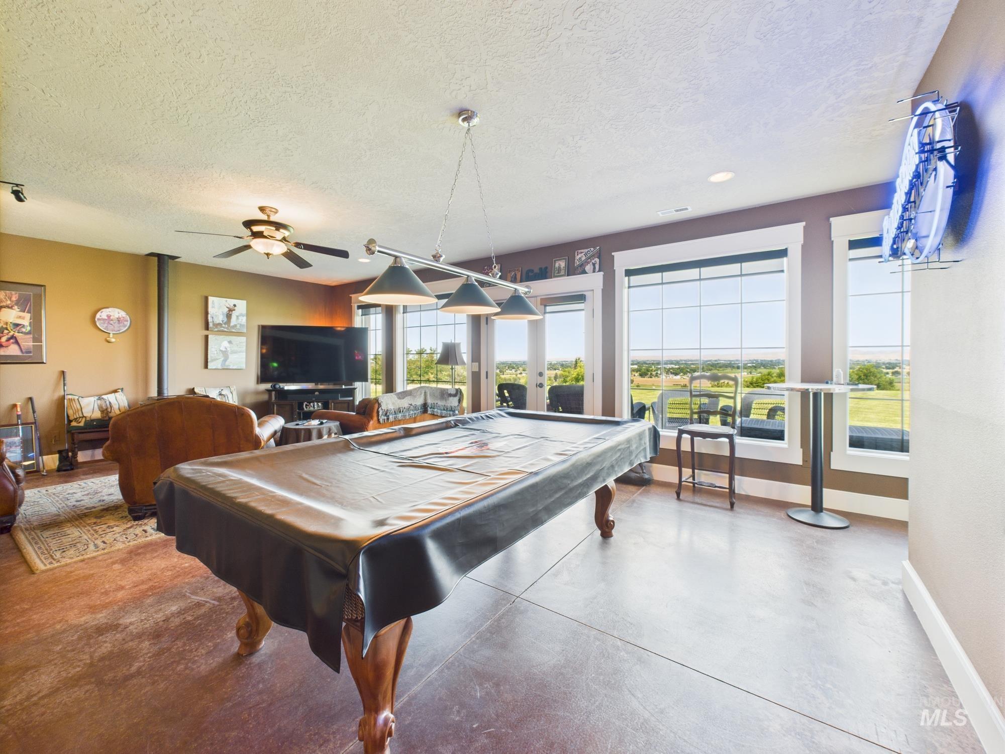 Rec room featuring french doors, concrete flooring, a textured ceiling, and pool table