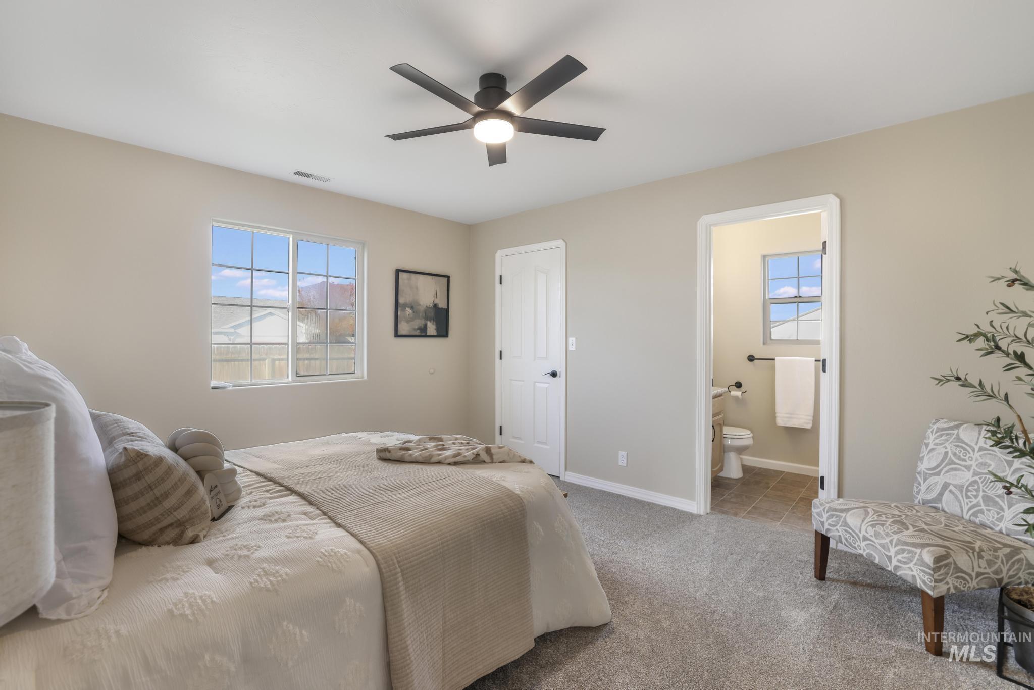 Bedroom with carpet floors, a ceiling fan, and ensuite bath