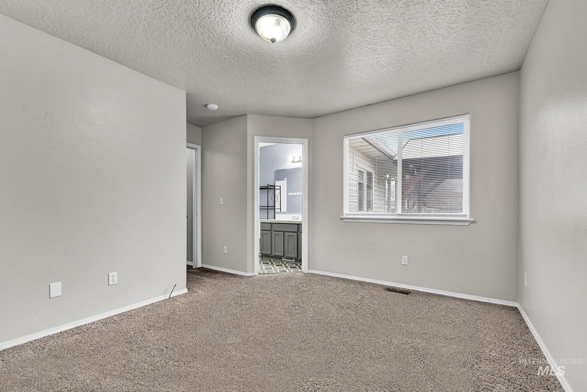 Carpeted empty room featuring baseboards and a textured ceiling
