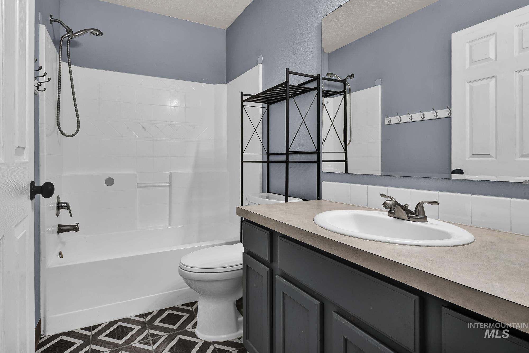 Bathroom with washtub / shower combination, vanity, and a textured ceiling