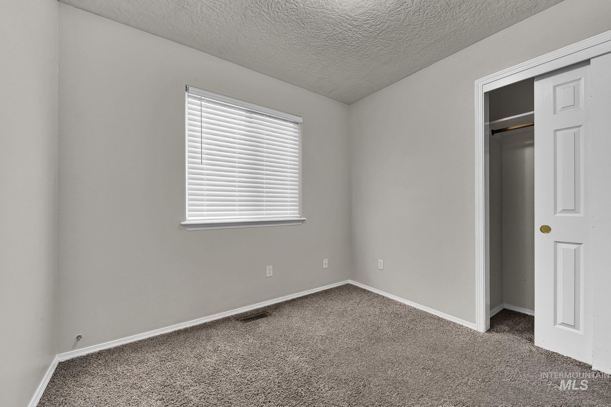 Unfurnished bedroom with carpet floors, a textured ceiling, and a closet