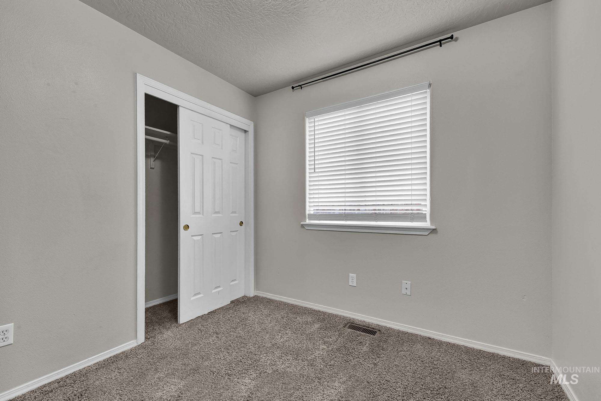 Unfurnished bedroom with carpet floors, a textured ceiling, and a closet
