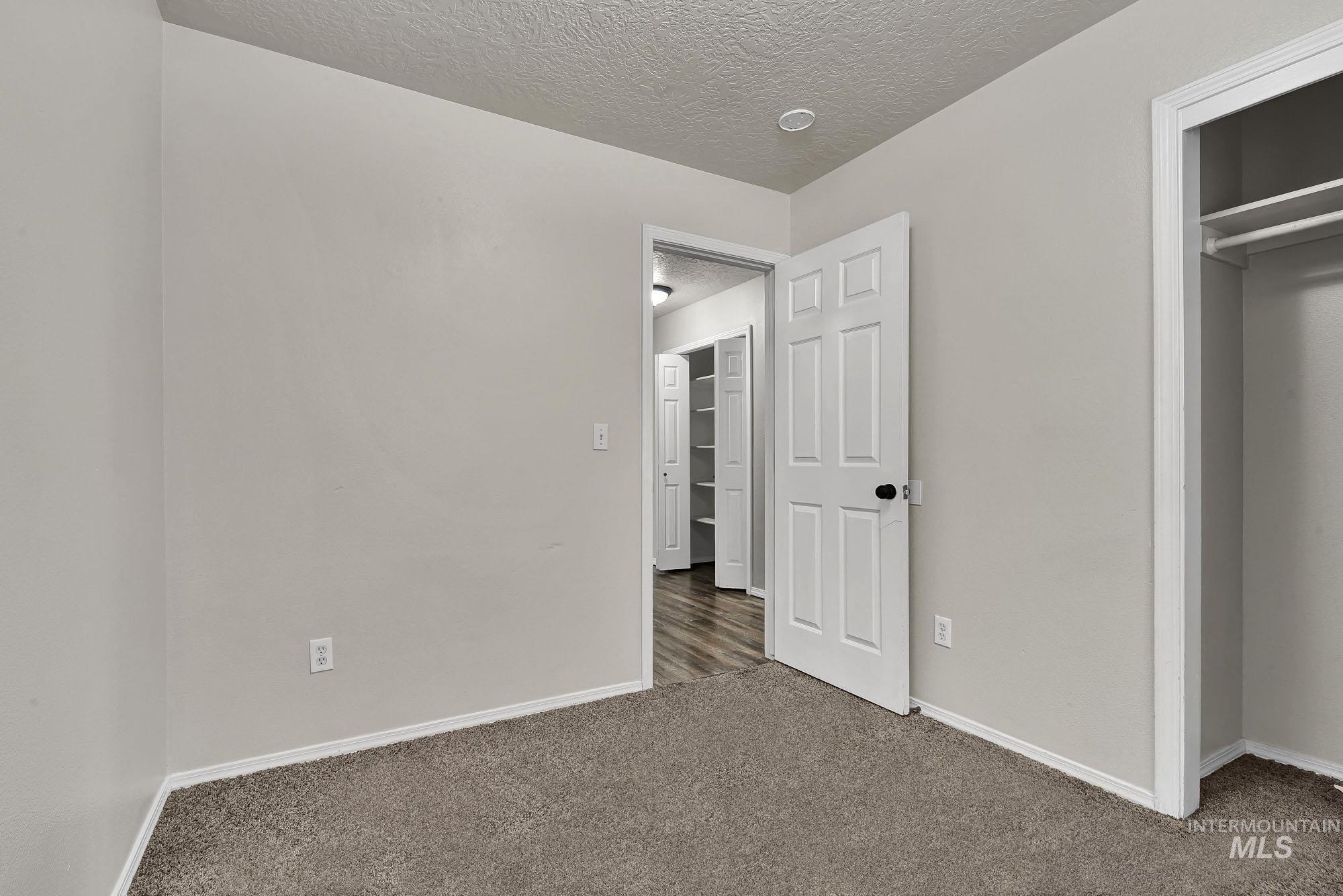 Unfurnished bedroom with carpet flooring, a textured ceiling, and a closet