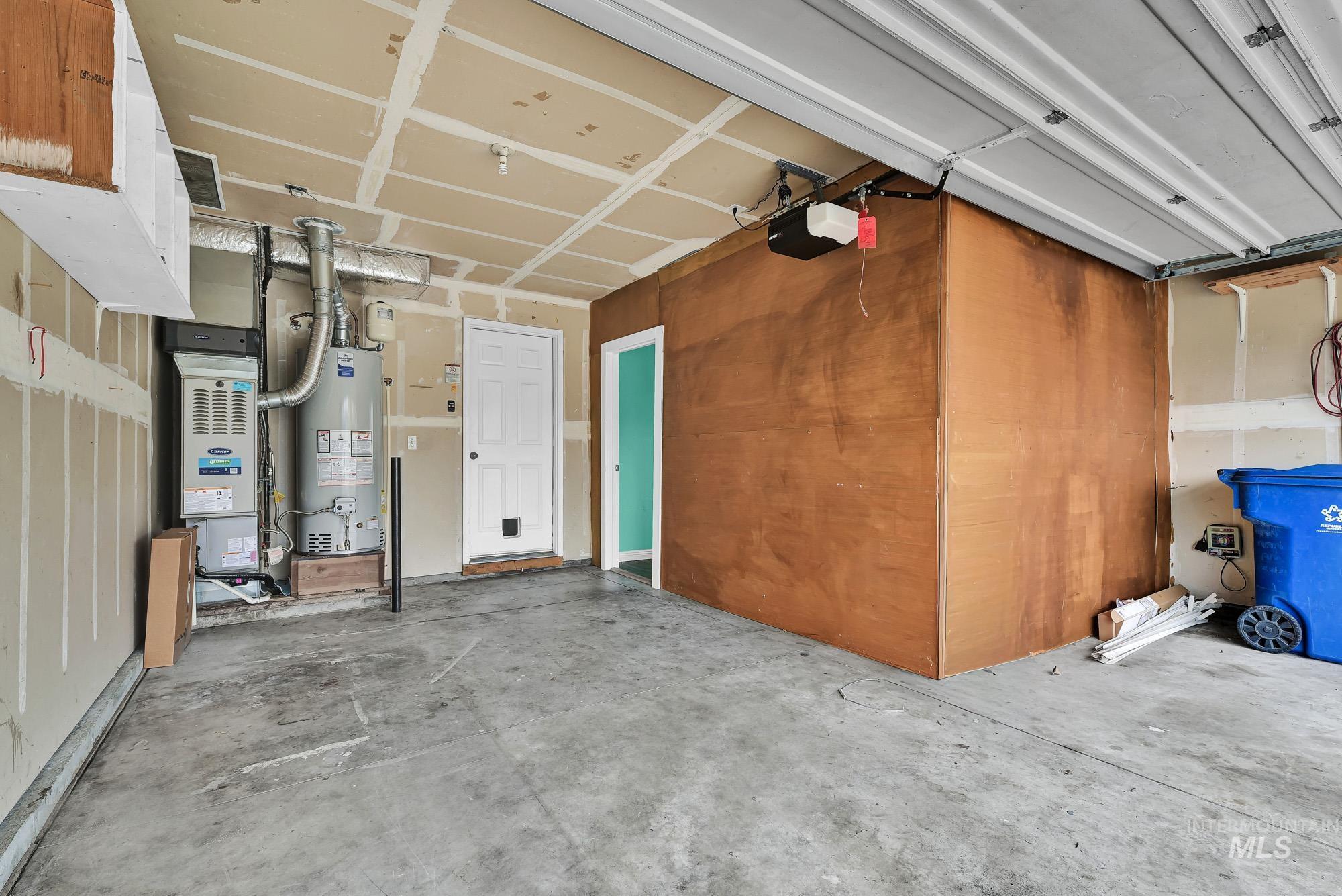 Garage with water heater, heating unit, and a garage door opener