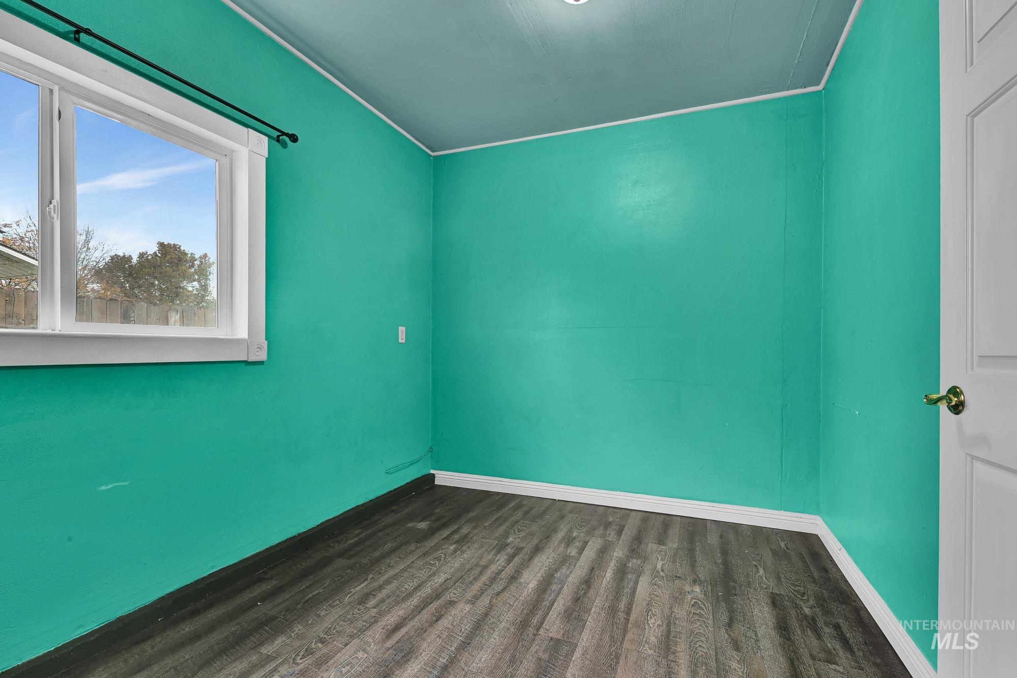 Unfurnished room featuring dark wood-type flooring and baseboards