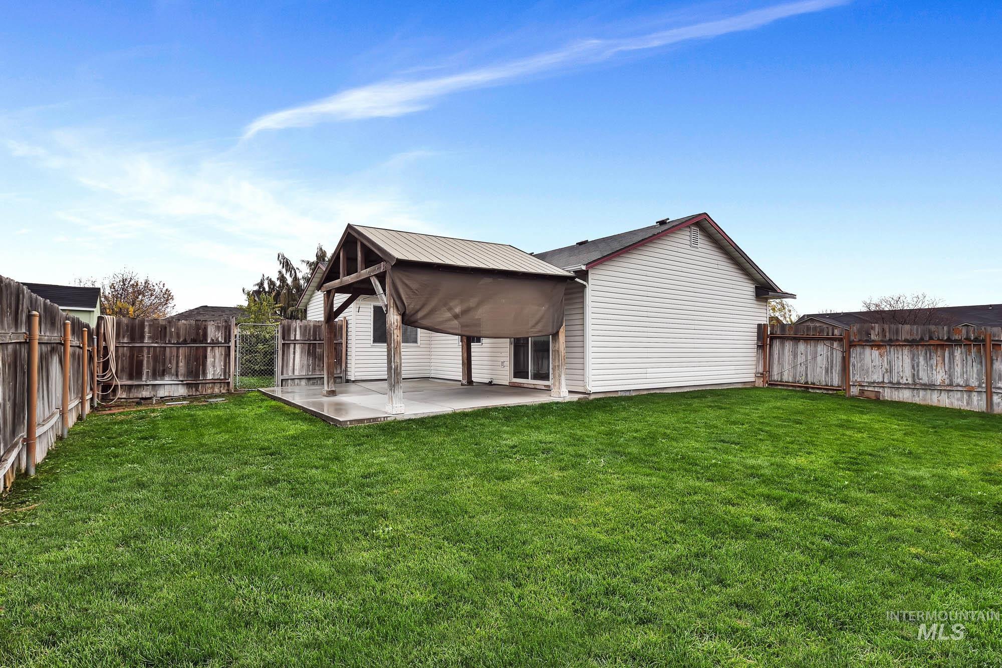 Rear view of property featuring a fenced backyard, a gate, and a metal roof